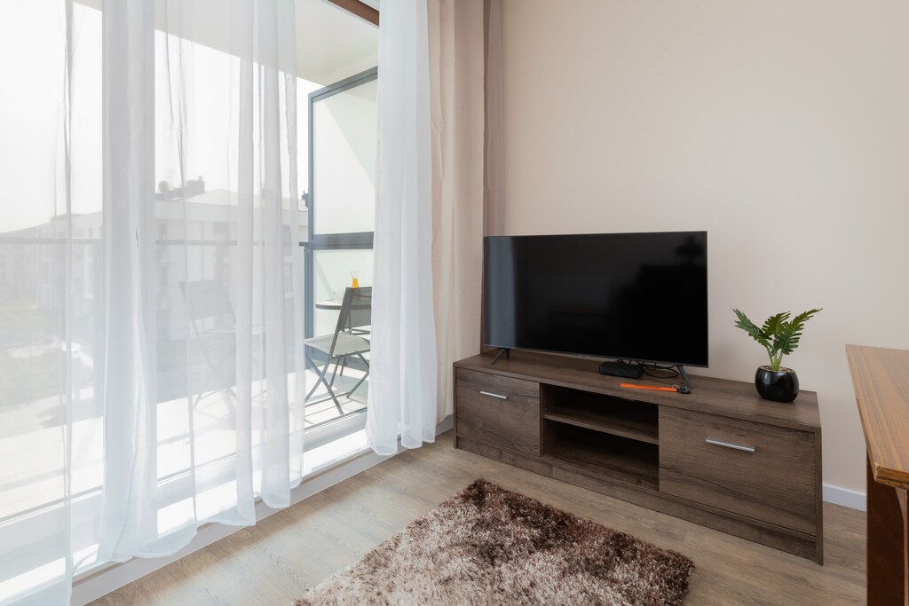 A view of the living area featuring a modern TV unit, a flat-screen TV, and access to the balcony.