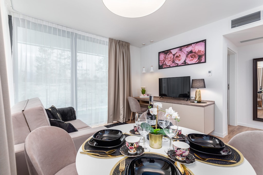 Close-up of a dining table with elegant black tableware. In the background you can see the flat-screen TV that will provide evening entertainment.