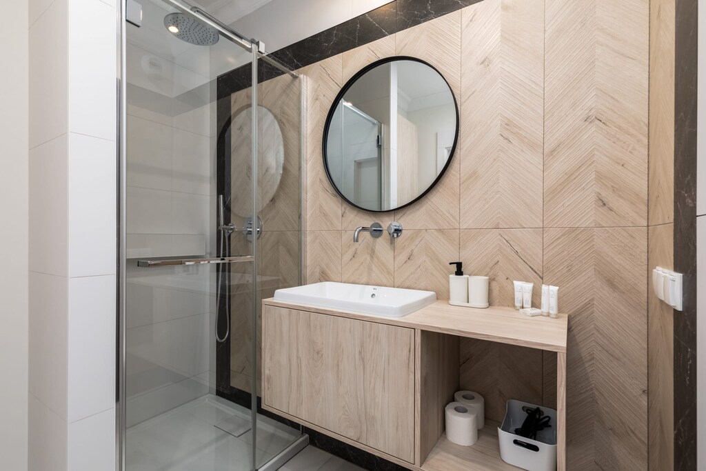 A modern bathroom with a shower, toilet, sink with mirror and elegant lighting.