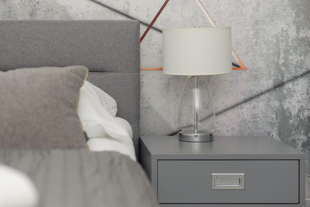 A close-up of a bedside table with a lamp, showcasing the cozy bedroom decor.
