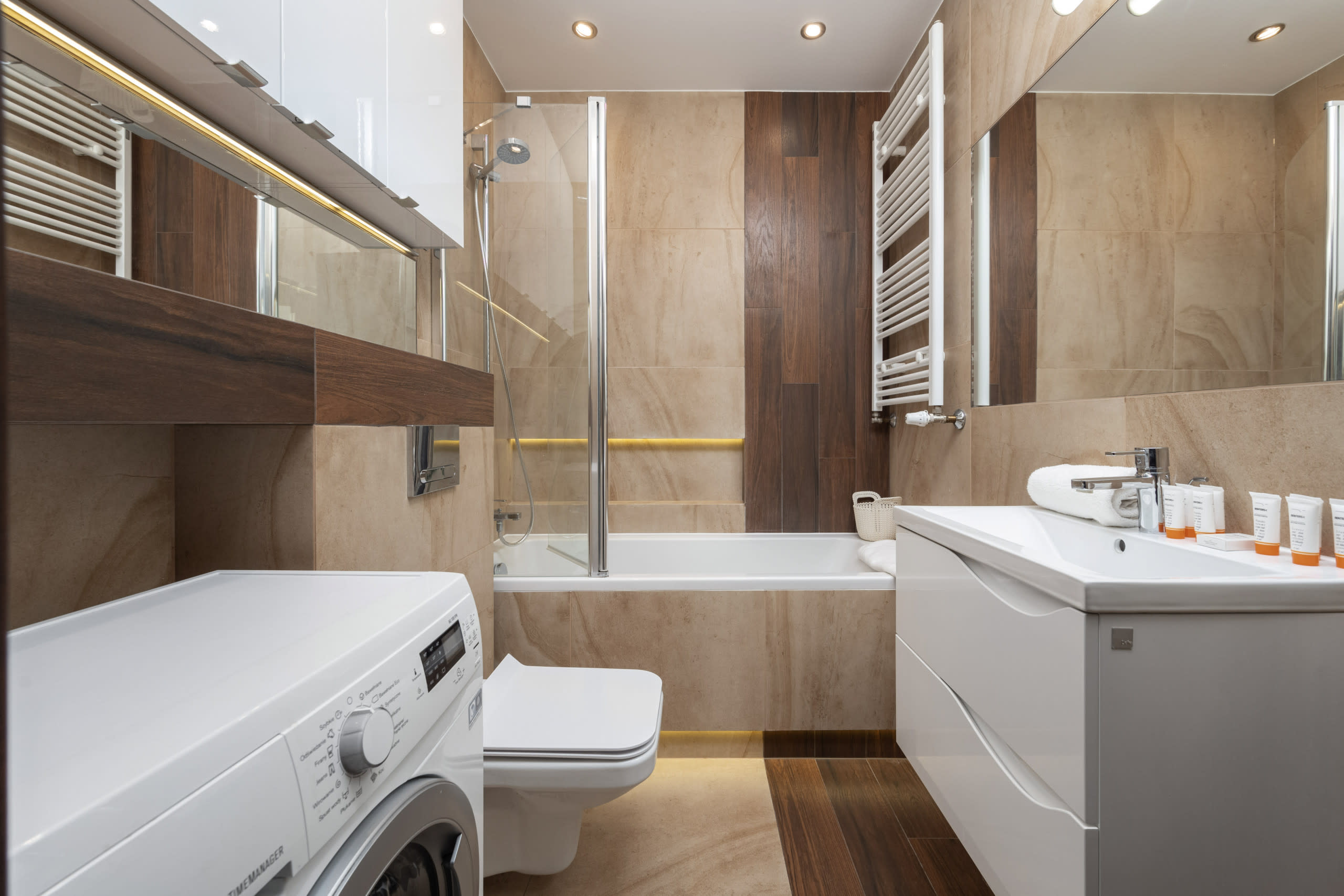 Bathroom with beige tiles, a washing machine, and a compact modern design.
