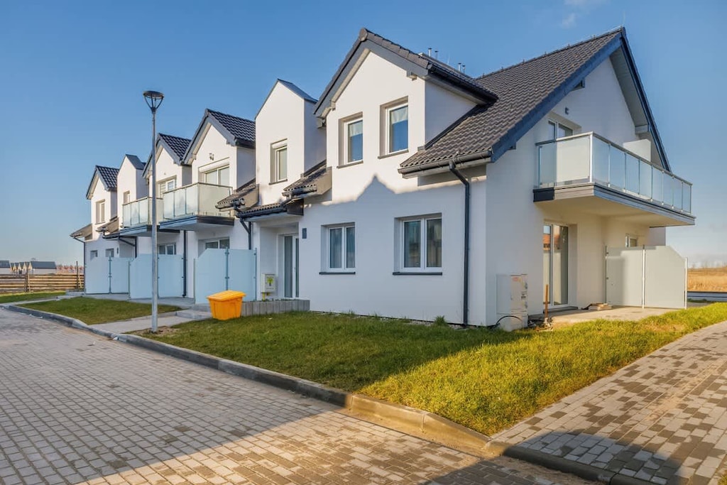 An exterior view of charming townhouses with modern architecture and neatly landscaped surroundings.
