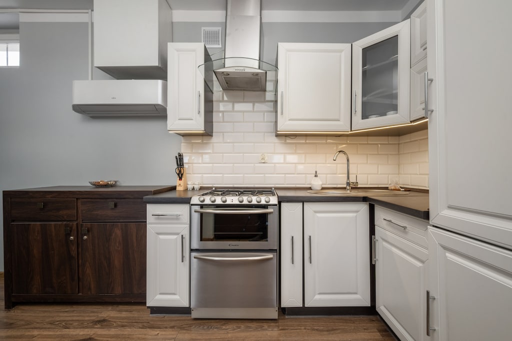 Another angle of the modern kitchen, showing white cabinetry, a countertop, and a dining area in the background.