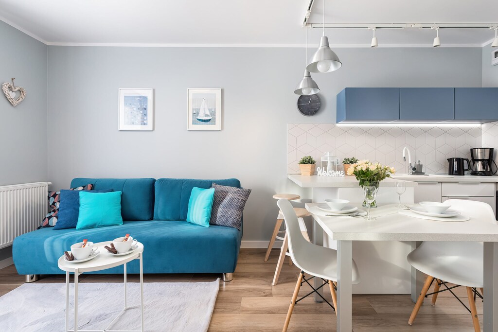 A modern living room decorated in shades of blue and white, featuring a cozy blue sofa with matching pillows, a minimalist coffee table, and bright natural lighting from large windows.