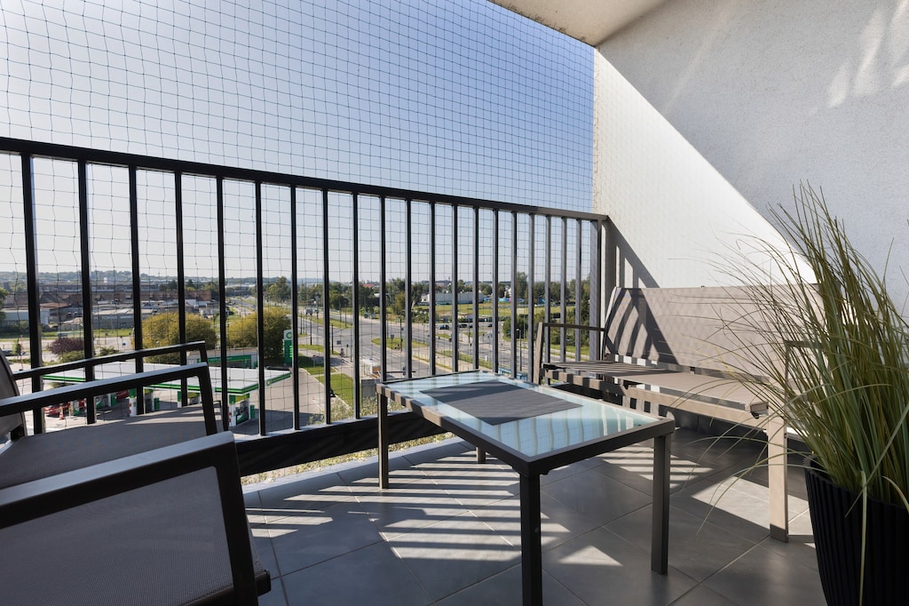 A spacious balcony with a seating area and a decorative railing, offering a relaxing outdoor retreat with urban views.
