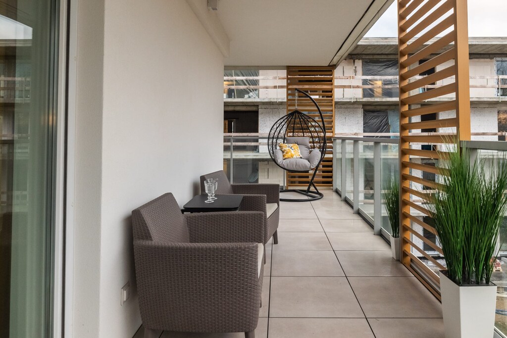 Spacious furnished balcony with two armchairs, a table and a hanging chair which is an ideal place to relax.