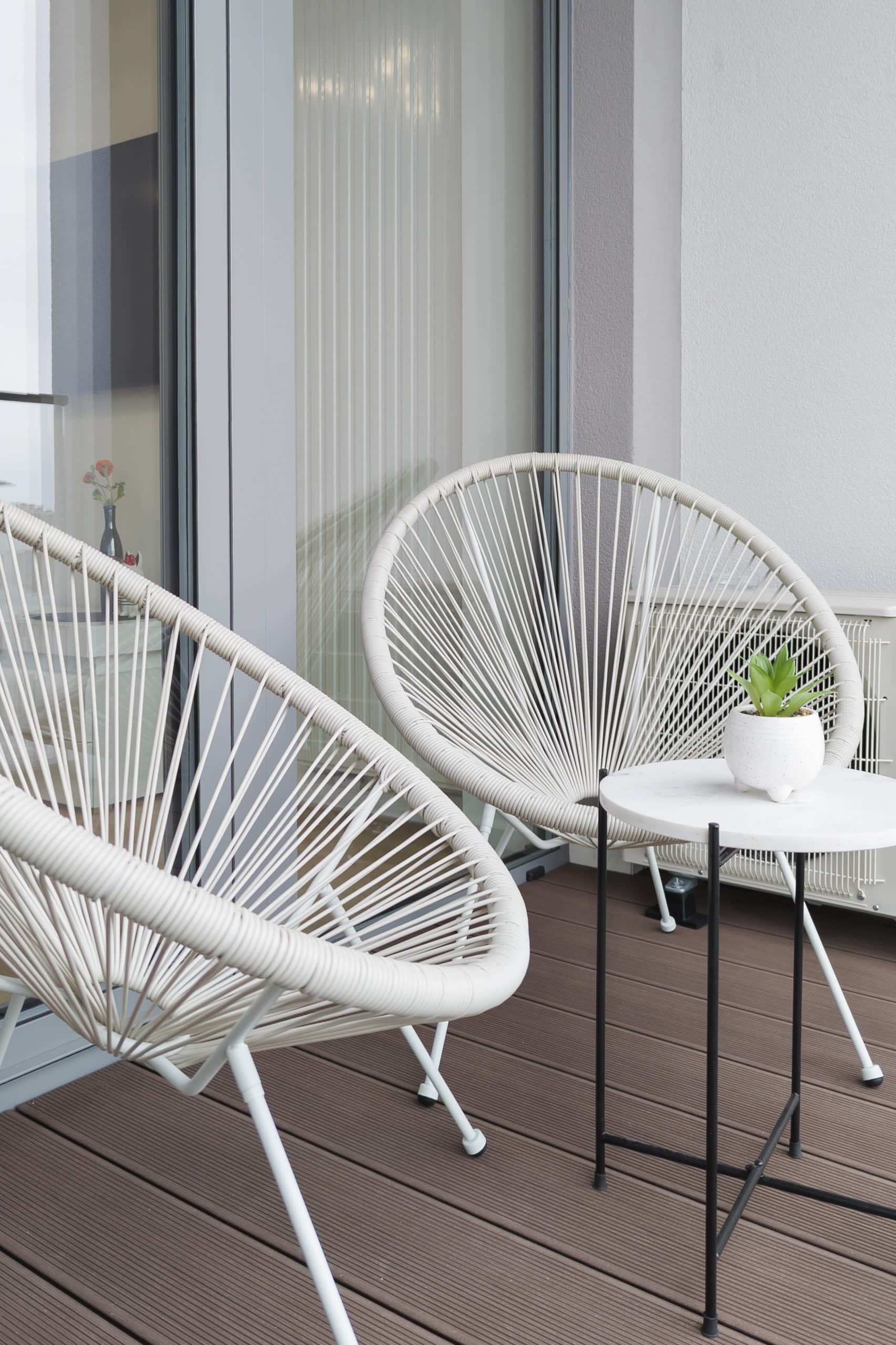 Outdoor seating on the balcony with minimalist chairs and a side table, perfect for relaxation.
