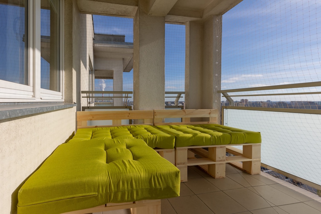An outdoor terrace with modern furniture and a green turf-style rug.
