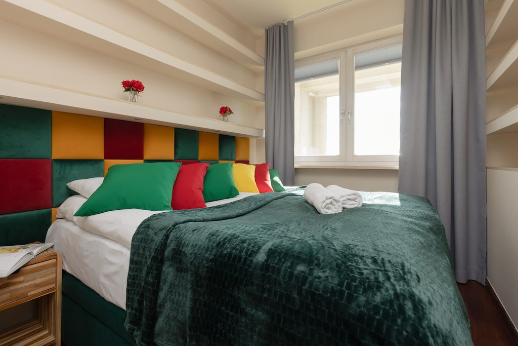 A bedroom with a double bed, green bedding, and soft lighting.
