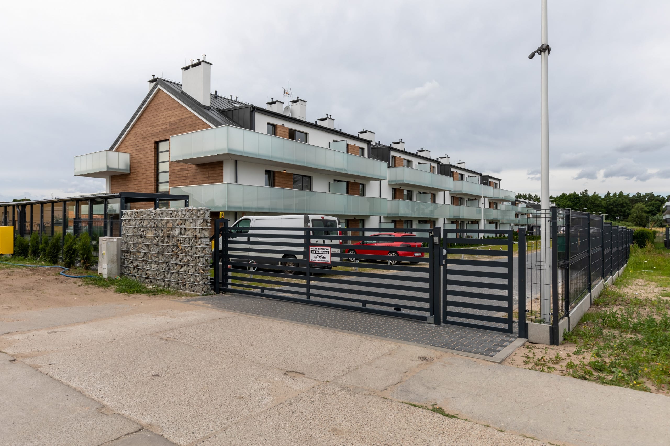 A driveway leading to a multi-unit building, with a modern design and gated entrance.