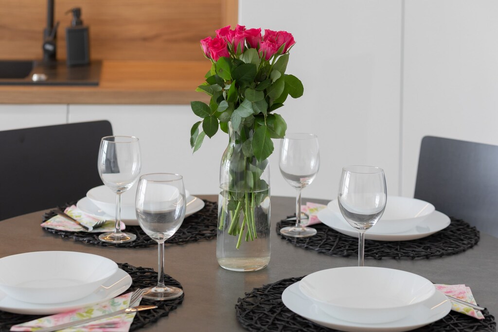 A dining table elegantly set for a meal, decorated with flowers and neatly arranged tableware.