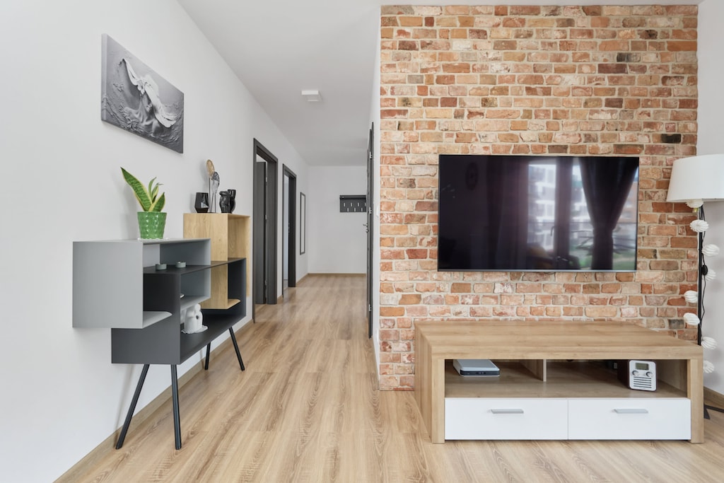 A living area with a TV mounted on a brick accent wall, offering a stylish design.

