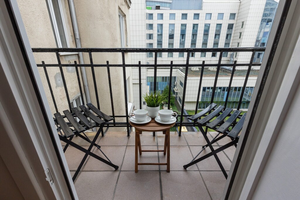 A balcony offering city views, complete with a small table and chairs for outdoor relaxation.

