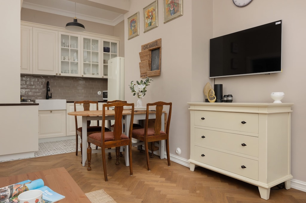 An open-plan kitchen and dining area with a vintage-inspired design and a flat-screen TV.

