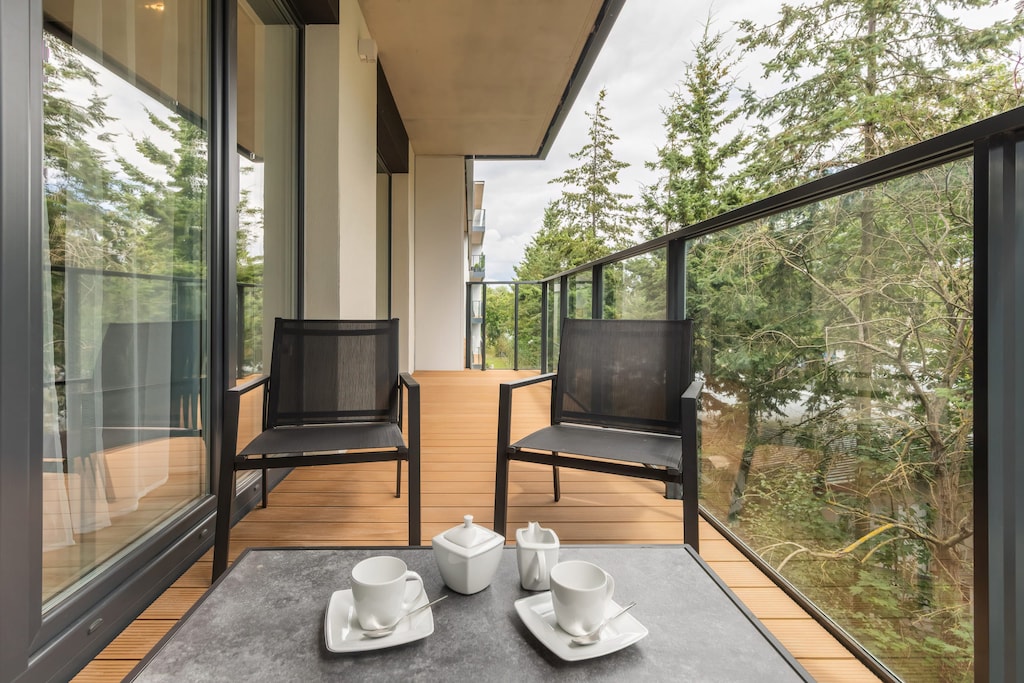 A spacious balcony with two chairs, a small table, and a view of the surrounding greenery, perfect for enjoying a morning coffee or evening sunset.

