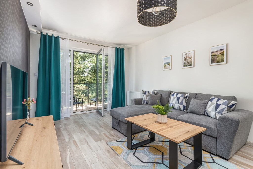 A bright living room with a large sectional sofa, a wooden coffee table, and modern decor, offering a comfortable and stylish relaxation area.

