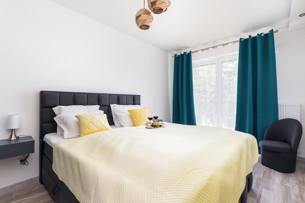 A cozy bedroom featuring a yellow bedspread, teal curtains, and minimalist decor that creates a warm and inviting ambiance.

