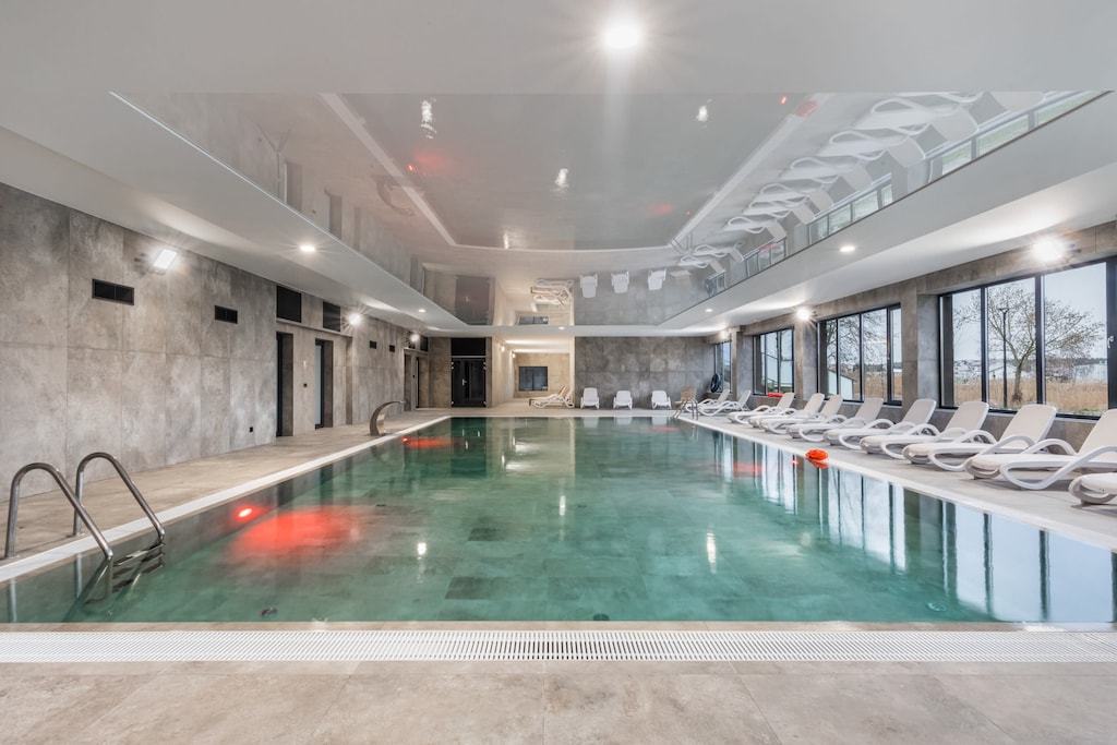 Luxurious indoor pool with modern lighting and a large relaxation area.
