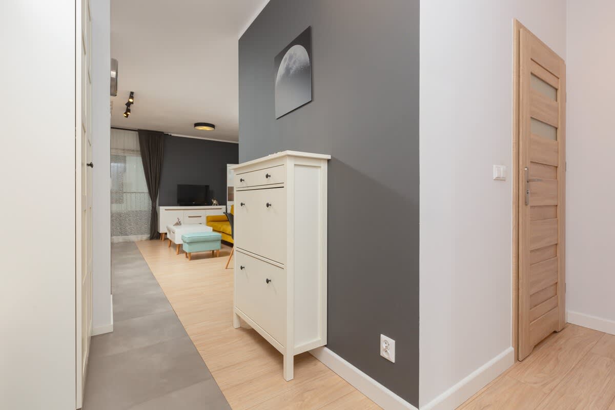 A simple hallway with neutral tones and wooden flooring. It connects the living spaces with doors leading to different rooms.