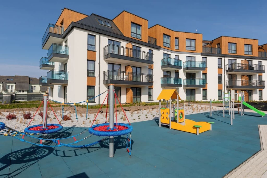 An exterior view of the residential complex with colorful facades, a playground, and open community spaces.
