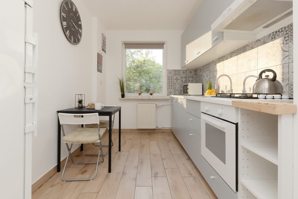 An open-concept kitchen and dining area with modern appliances, a small dining table, and a large window.
