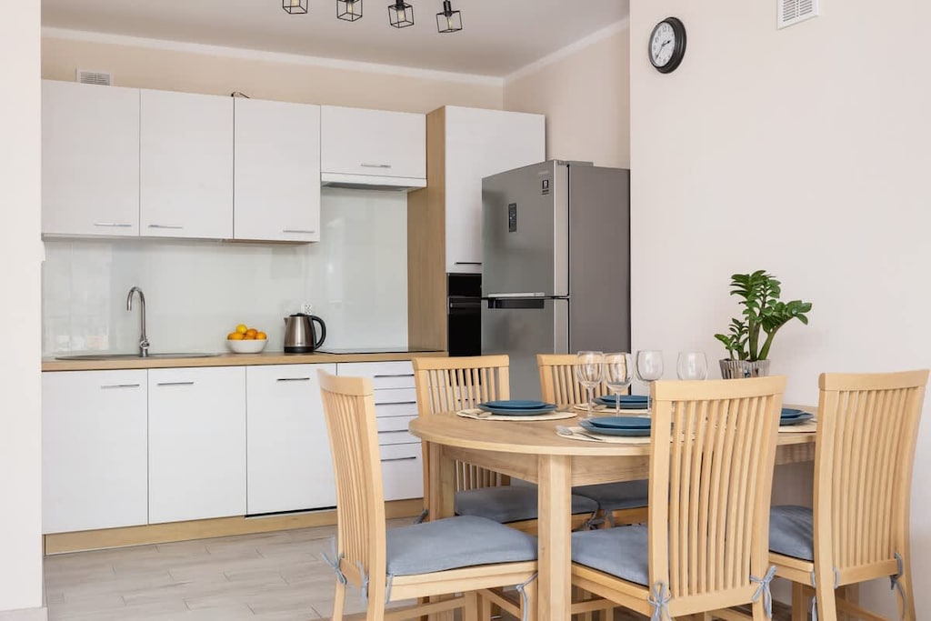 A modern kitchen with wooden cabinets and a dining table surrounded by chairs, giving a homely vibe.