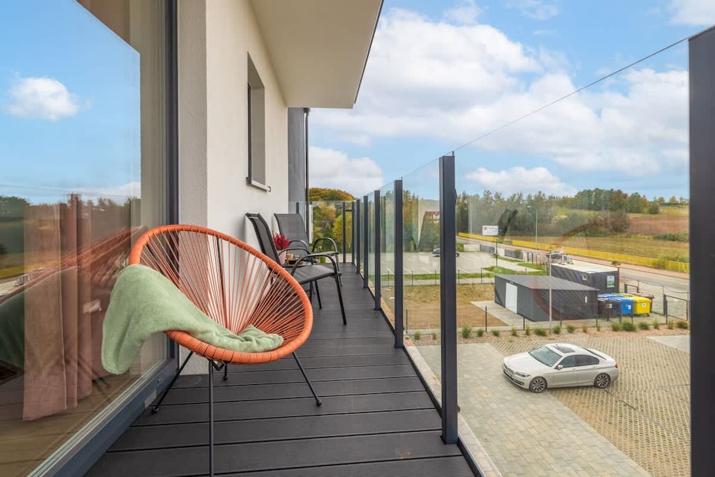 A balcony view overlooking a parking area with a hanging chair in the corner.

