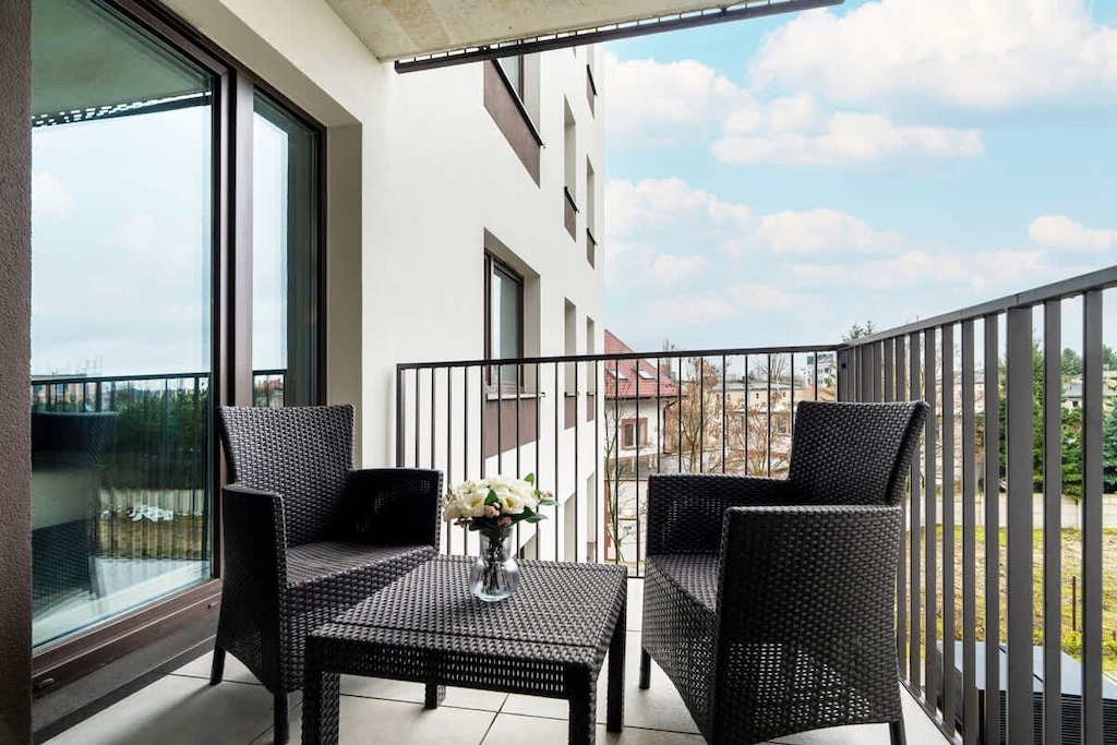 A spacious balcony with a black outdoor seating set, offering a relaxing spot with a view of the surroundings.

