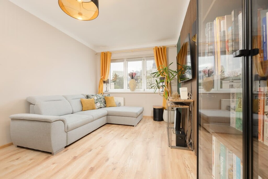 A bright, open living room with a beige sofa and stylish decor, featuring a large mirror and wood-toned accents.