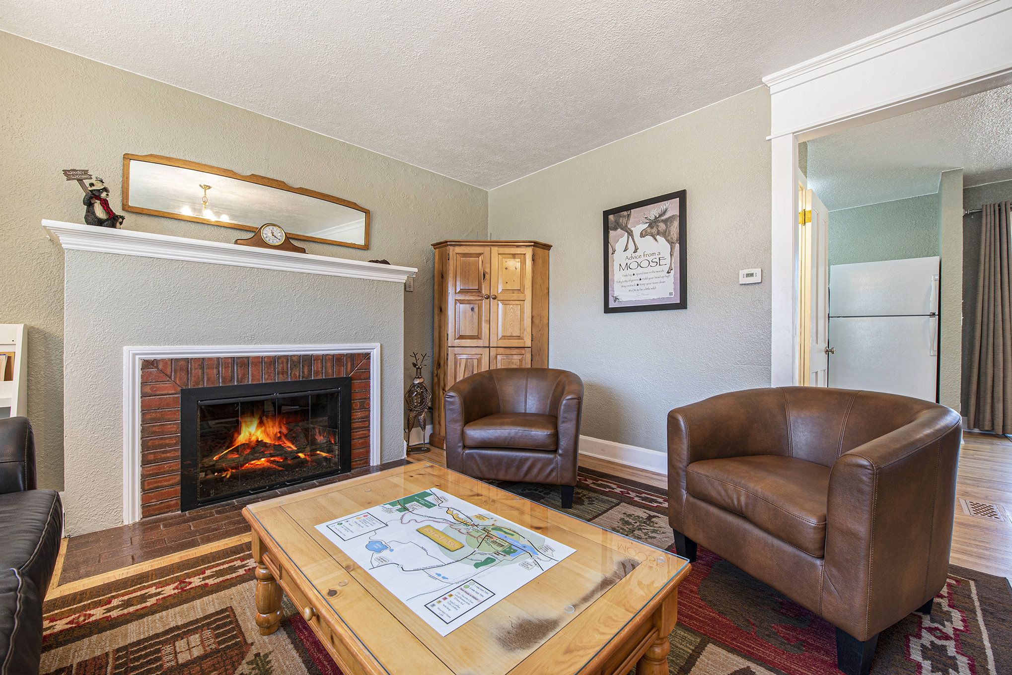 Your Vacation House Estes Park, Living room with 2 arm chairs, coffee table, gas fireplace, and armoire tv stand.