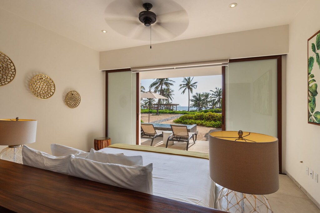 Wake up to paradise in this master suite, featuring a private oceanfront patio, minimalist decor, and natural lighting.
