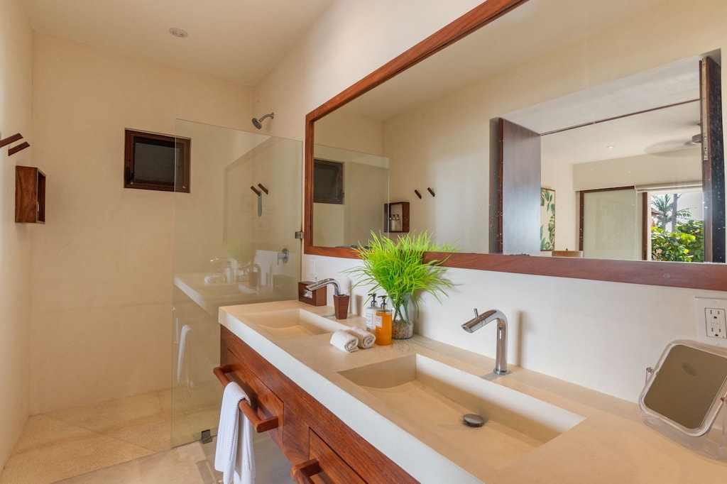 A luxurious bathroom featuring sleek double vanities, a rainfall shower, and warm wooden accents for a spa-like feel.