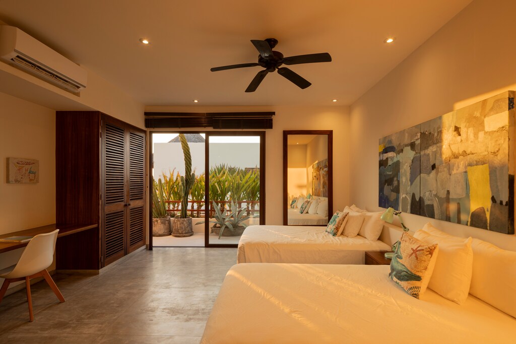 This stylish bedroom features plush bedding, modern furnishings, and a balcony with ocean views.