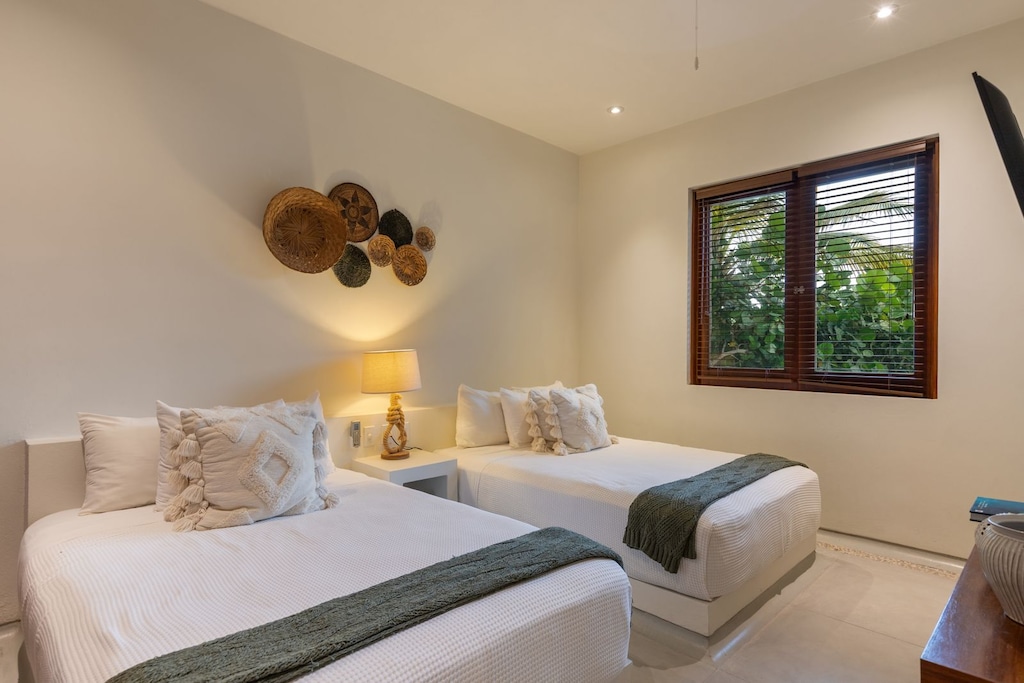 A cozy and stylish twin bedroom featuring soft textures, rustic decor, and peaceful garden views.