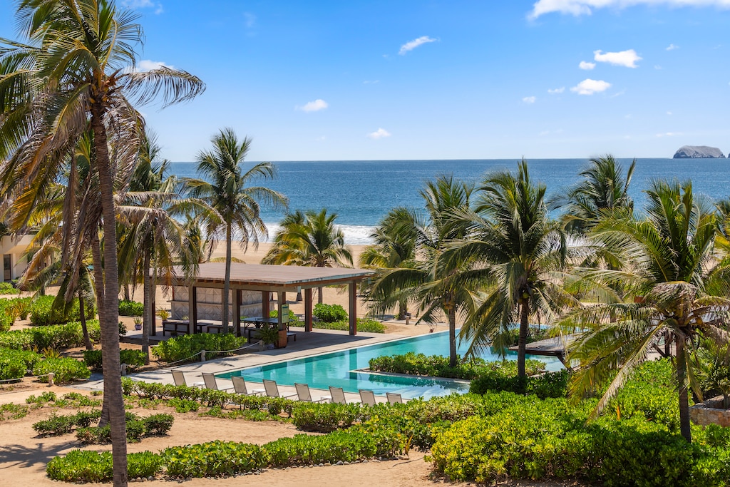 With this stunning beachfront pool surrounded by palm trees in Playa Blanca, Zihuatanejo. Enjoy uninterrupted ocean views, direct beach access, and a luxury beach club experience just steps from your villa.