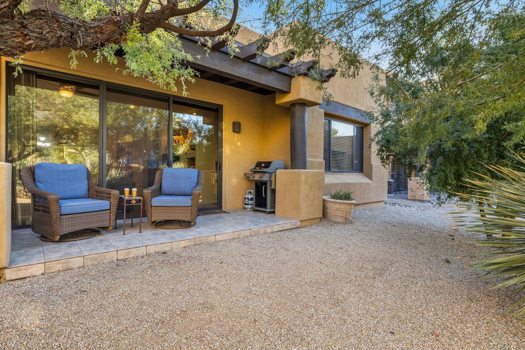 Covered patio with wicker seating and a grille, perfect for dining or relaxing