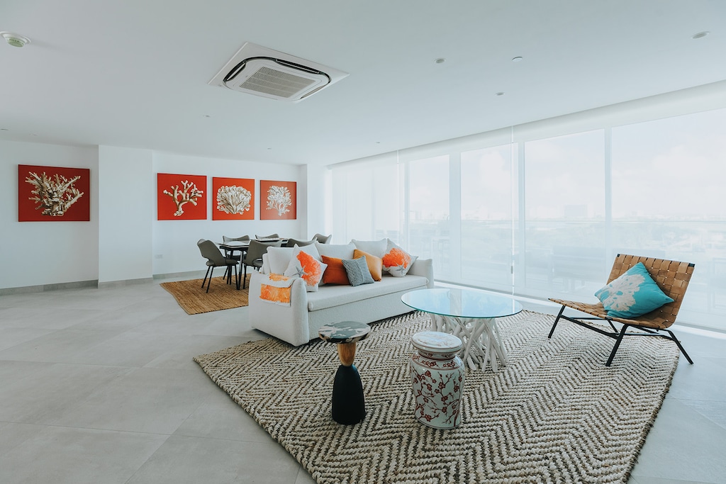 Your bright, open living space features coastal artwork, plush seating, and floor-to-ceiling windows flooding the room with natural light and sweeping views.