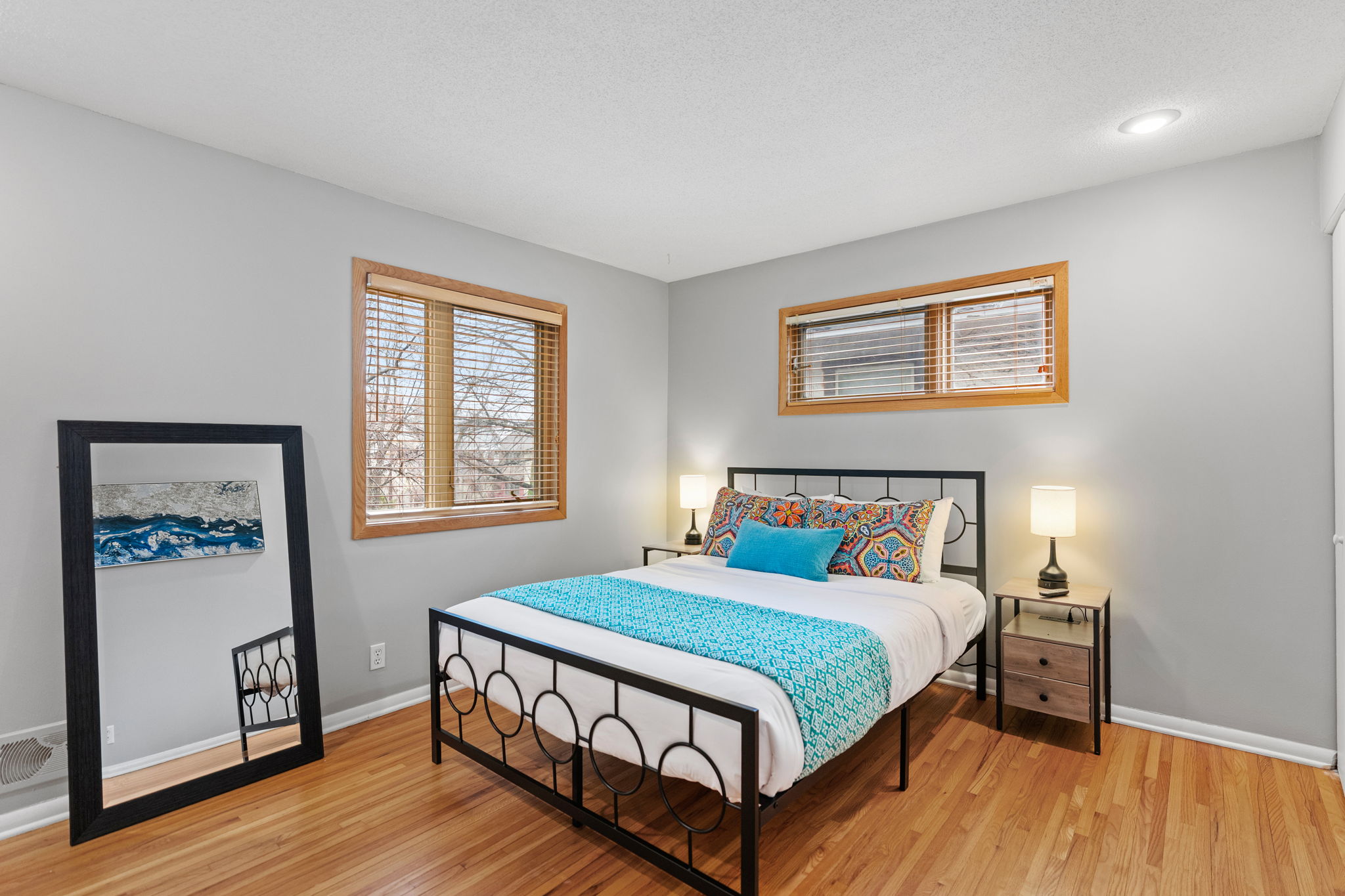 Sink into this peaceful bedroom where warm wood floors and soft lighting create your perfect retreat after exploring the day.