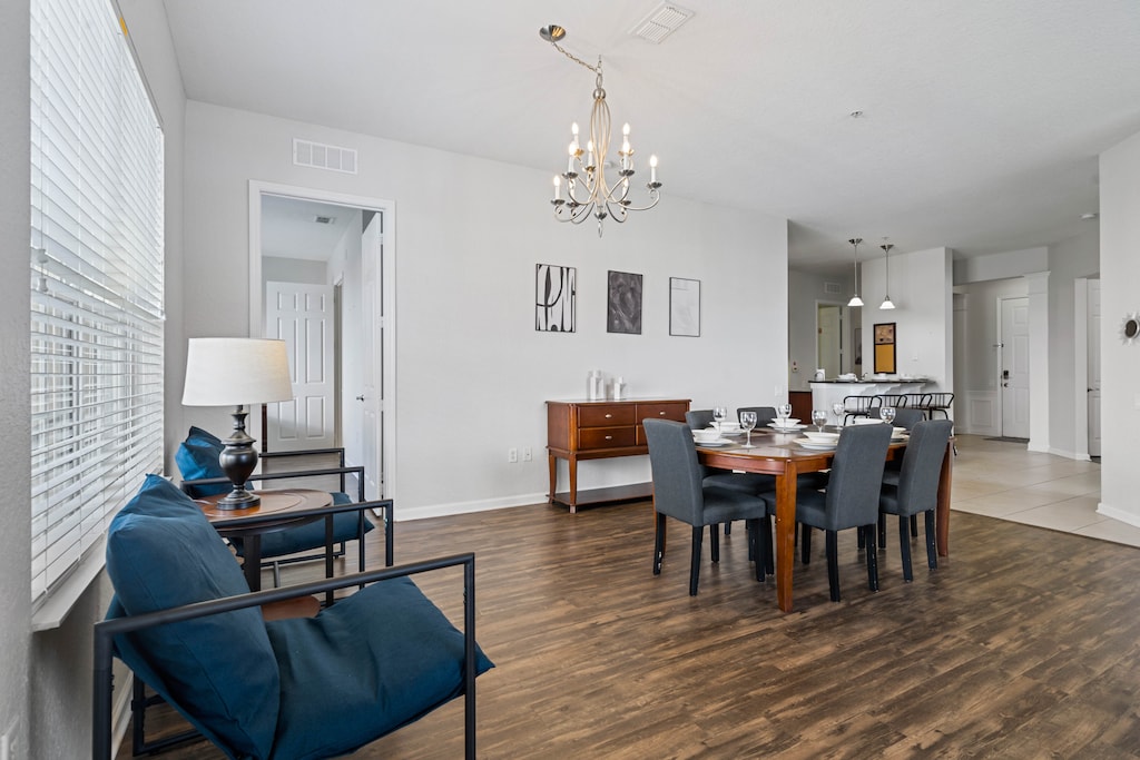 - Open dining area complemented by a cozy seating nook with stylish blue chairs - Tasteful decor, hardwood floors, & modern chandelier create a sophisticated atmosphere - Seamless connection to the kitchen and living areas for effortless entertaining