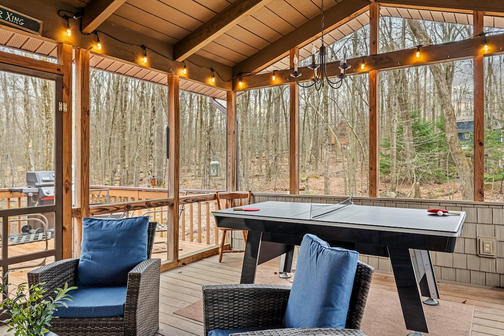 Screened-in porch with forest view and ping pong table.