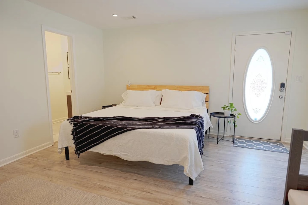 Relax in this spacious bedroom with a king-sized bed, soft lighting, and a touch of greenery for a peaceful retreat.