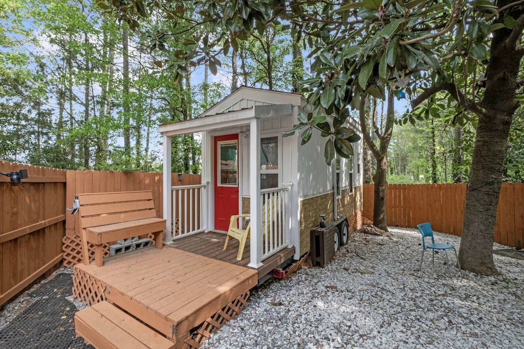 Relax in this charming outdoor retreat with a vibrant red door, cozy seating, and a serene fenced yard perfect for unwinding.