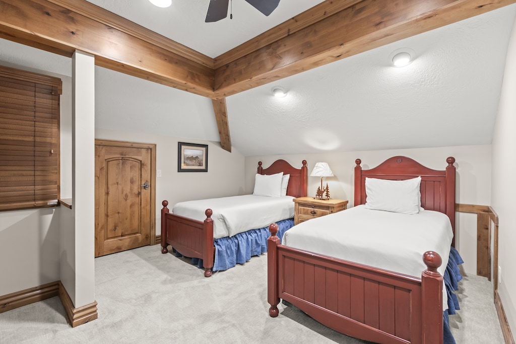 Relax in this cozy twin bedroom featuring wood beams and charming red beds with crisp white linens.