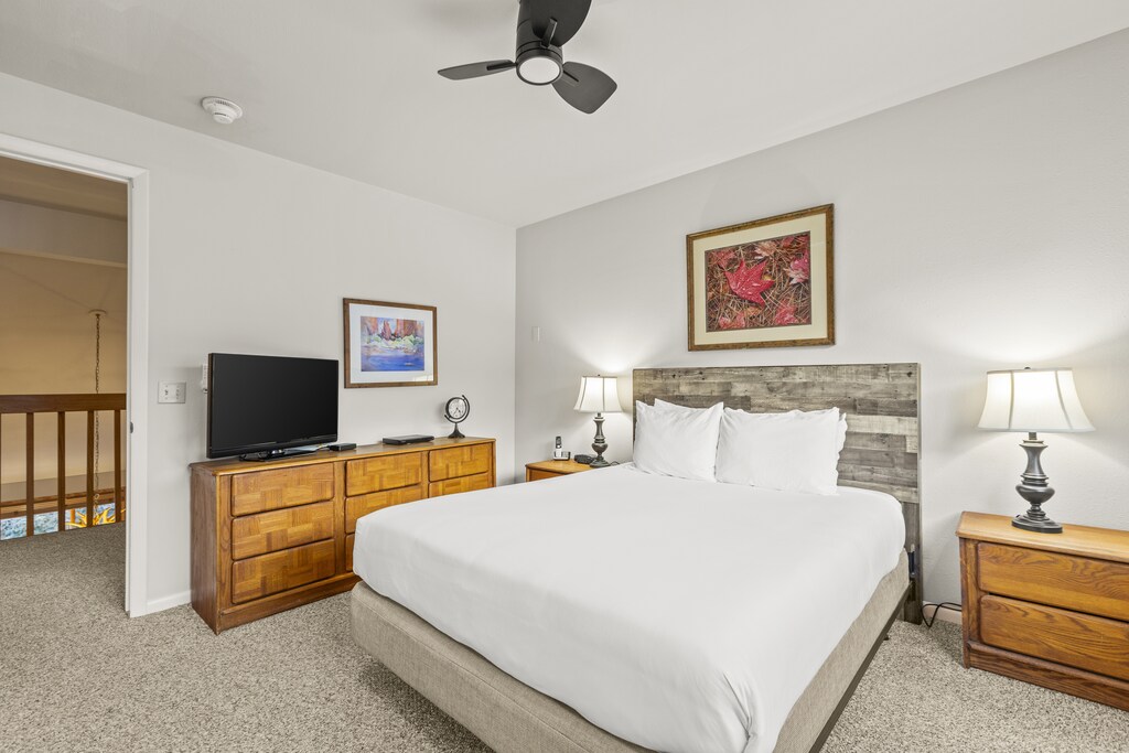 The bedroom with a queen size bed, wood dresser, and flat screen TV.