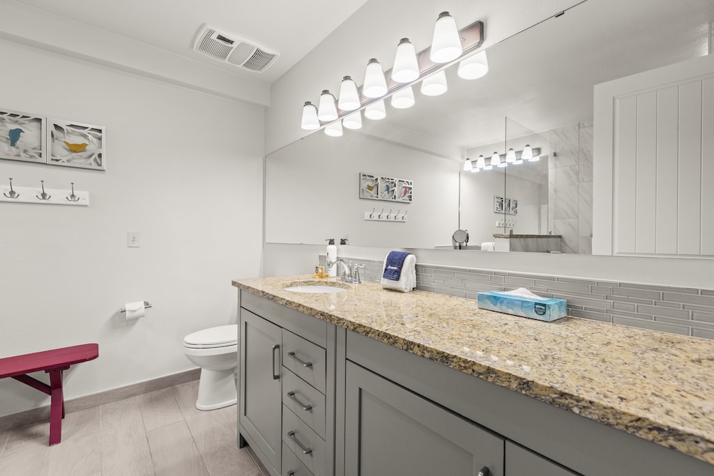 The en suite bathroom has a double sink vanity and granite countertops.