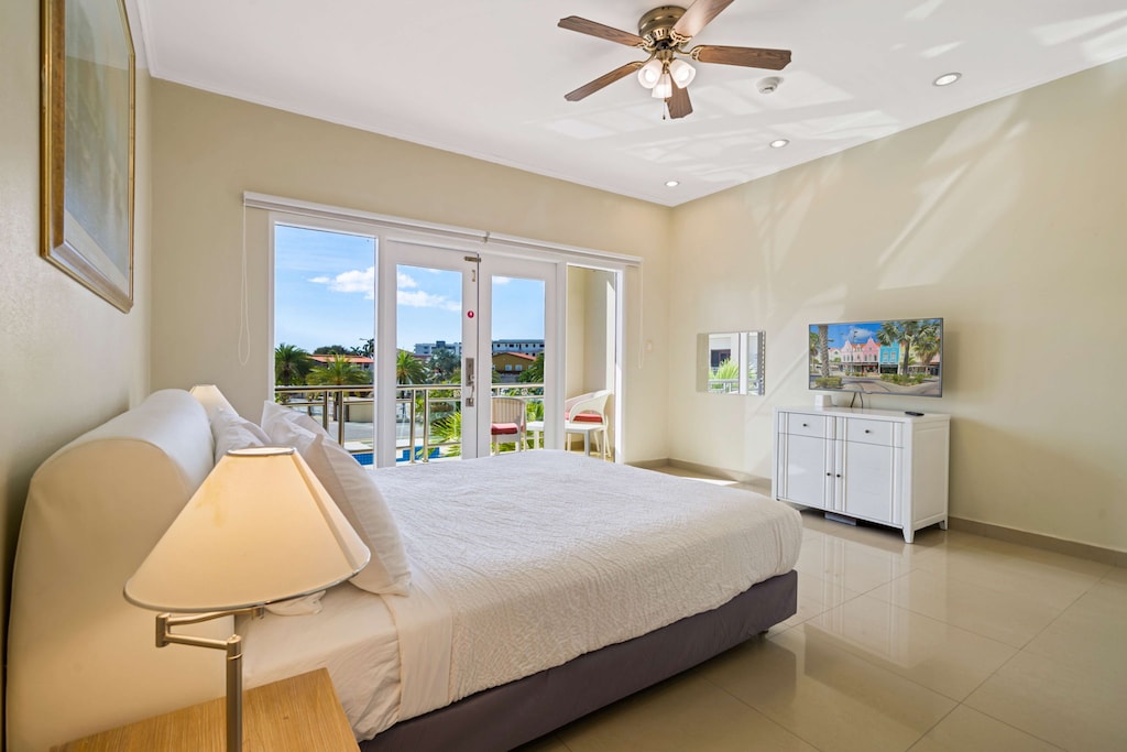 Wake up to stunning tropical views in this spacious bedroom, featuring a plush king bed, private balcony access, and a flat-screen TV for ultimate comfort and relaxation.
