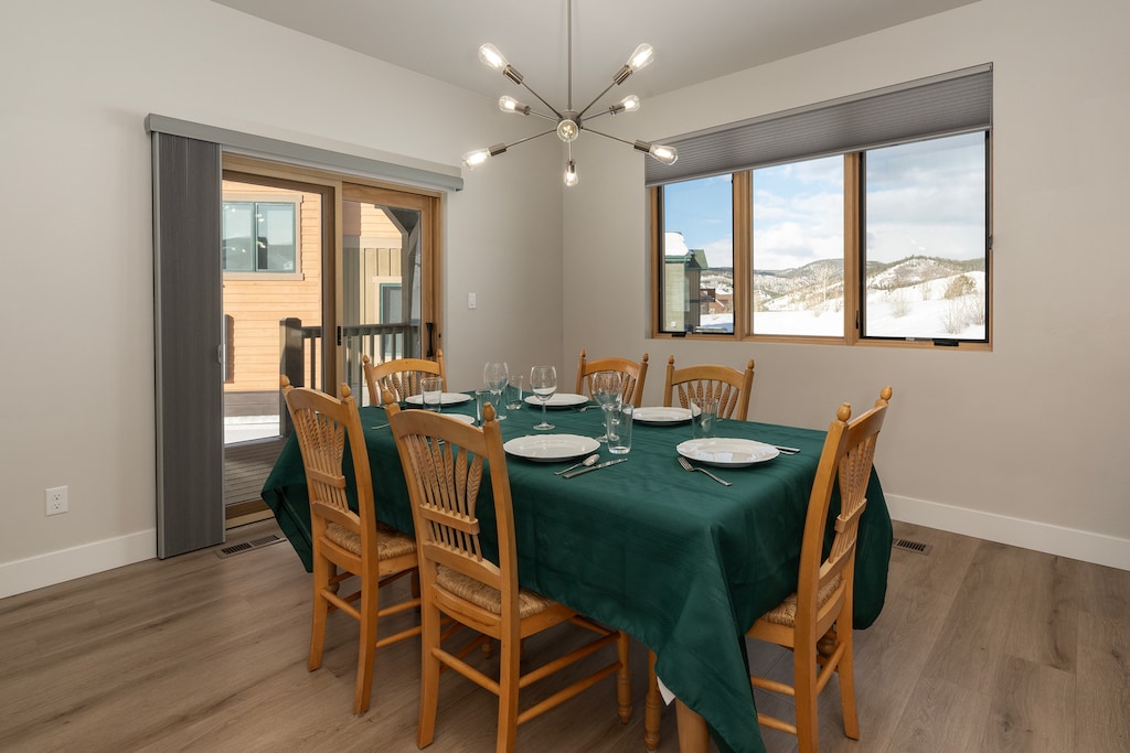 - Gather around this spacious dining table set for six with bright natural lighting - Sliding doors lead to a private deck, perfect for outdoor meals or morning coffee - Scenic mountain views through large windows create a warm, alpine dining vibe