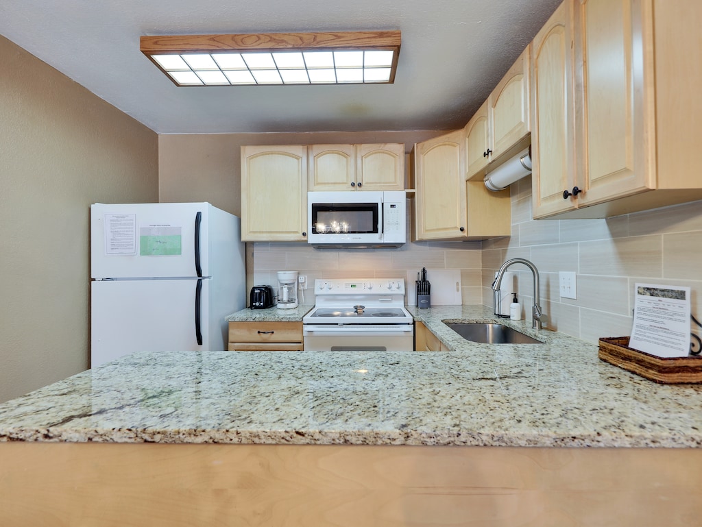 Fully stocked kitchen with stone countertops, a tile backsplash, and all the amenities needed to prepare meals after a day on the slopes