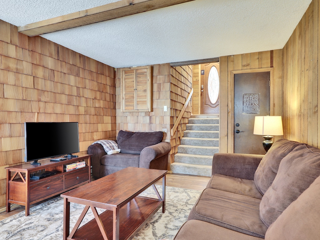 View of the inviting living room featuring comfortable seating, a 55” smart TV, DVD player, and a cozy wood-burning fireplace