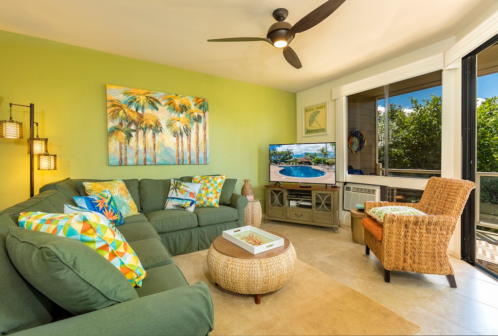 Relax in this bright and inviting living room, featuring comfortable seating, tropical décor, and large windows that fill the space with natural light.